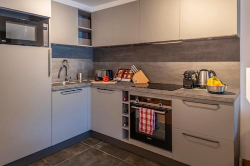 une cuisine avec des armoires blanches et un four à plaques de cuisson dans l'établissement Le Solaret B207, aux Gets