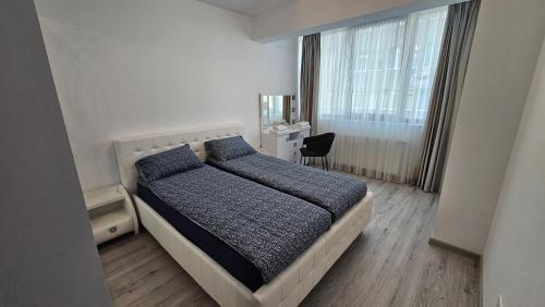 Schlafzimmer mit einem Bett, einem Schreibtisch und einem Fenster in der Unterkunft Nordic Residence 28 in Suceava