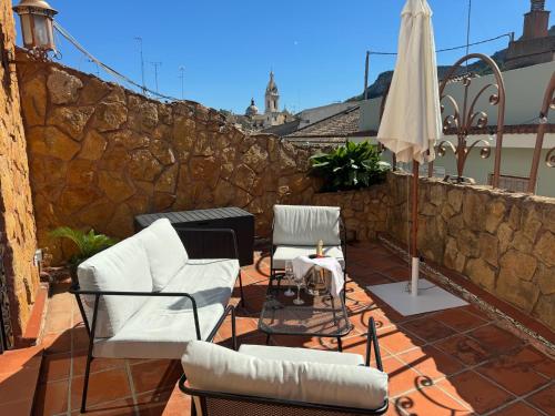un patio con due sedie e un ombrellone di Apartamento Dúplex de Lujo con Terraza y vistas al Castillo - Centro a Xàtiva