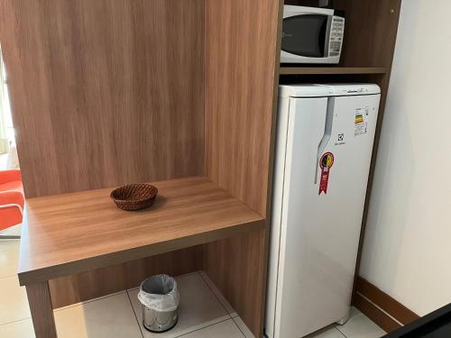 a kitchen with a refrigerator and a microwave on a shelf at Brasil flats - Athos Bulcão in Brasilia