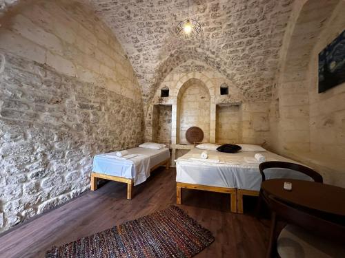 a room with two beds and a stone wall at Petra Hotel & Coffee House in Sanlıurfa