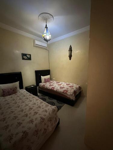 a bedroom with two beds and a chandelier at Villa Ms Holidays Mika privatisée Marrakech in Marrakech