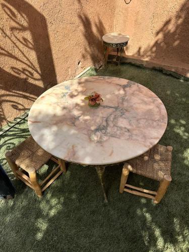 a marble table and two chairs on the grass at Villa Ms Holidays Mika privatisée Marrakech in Marrakech