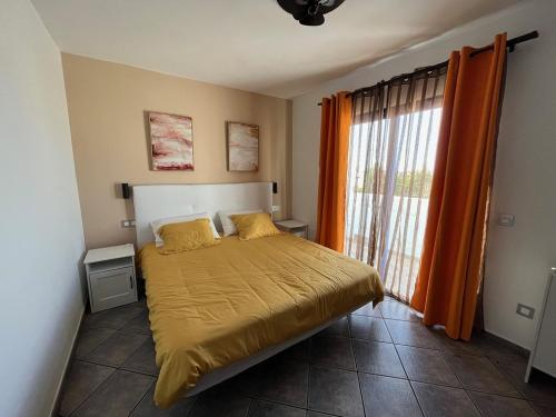 een slaapkamer met een bed en een raam met oranje gordijnen bij HOUSE WHITE BEACH in Playa Blanca