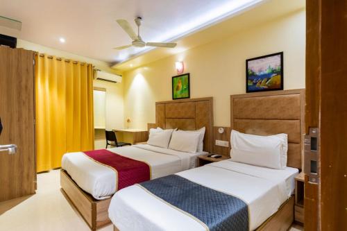 ムンバイにあるLOTUS GRAND HOTEL MUMBAIのベッド2台とテーブルが備わるホテルルームです。