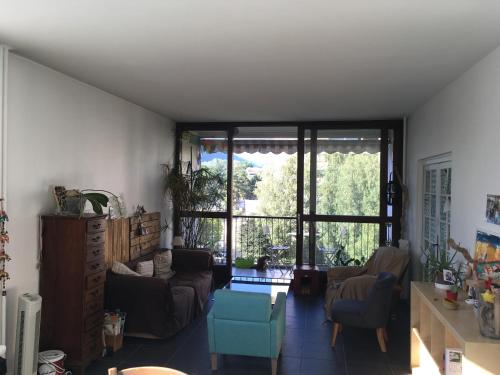 a living room with a couch and chairs and a large window at Chambre chez l'habitant avec toilettes et salle de bain privatifs in Annecy