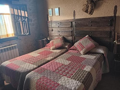 2 camas en un dormitorio con edredón y almohadas en CASA RURAL LA CASA DE LOS POLLOS, en Turrubuelo