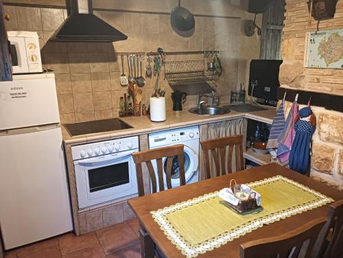 a kitchen with a table and a stove and a refrigerator at CASA RURAL LA CASA DE LOS POLLOS in Turrubuelo