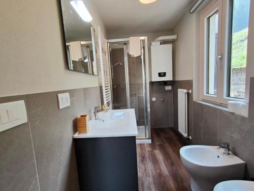 ein Badezimmer mit einem Waschbecken, einem WC und einem Spiegel in der Unterkunft Maison Carolina CIR-TORGNON-0004 in Torgnon