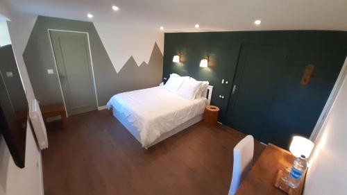 een slaapkamer met een wit bed en een groene muur bij Petit Manoir Proche Dinan in Lanvallay