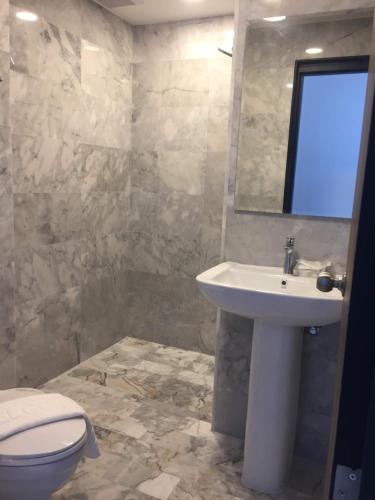 een badkamer met een wastafel, een toilet en een spiegel bij Mai Khao Beach Apartments in Ban Bo Sai Klang