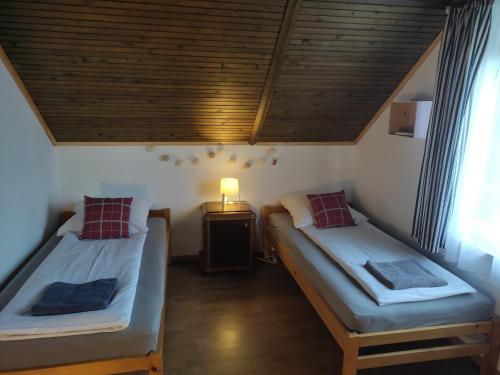 Cette chambre comprend deux lits et une lampe sur une table. dans l'établissement Kenderhordó Pihenőház, à Zánka
