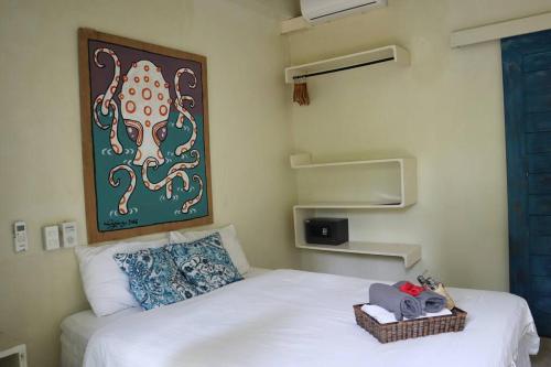 una camera da letto con un letto bianco con un dipinto sul muro di Sleepy Gypsea Villa Siargao - Private Room - Daydream a Catagnan
