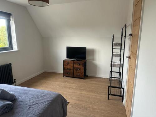 a bedroom with a television and a dresser with a bed at Grendon Close Near to Gatwick Airport in Horley