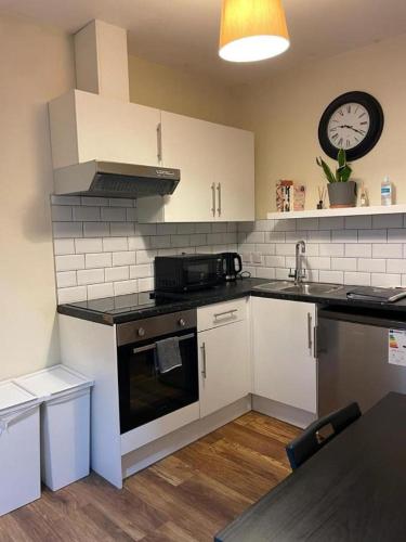 a kitchen with white appliances and a clock on the wall at Amazing Garden Studio 1 - Chingford/NE London in London