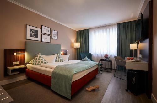 a hotel room with a bed and a desk at Hotel Metropol by Maier Privathotels in Munich
