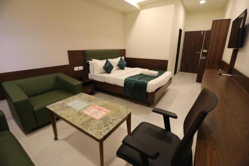 a hotel room with a bed and a table and a chair at Greenotel Rooms Hazira, Surat in Surat