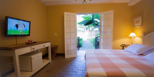 1 dormitorio con 1 cama y TV en la pared en Vila Bueno Residence en Jaguariúna