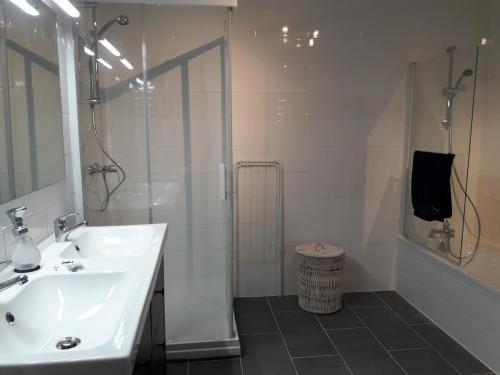 ein weißes Bad mit einem Waschbecken und einer Dusche in der Unterkunft Gîte breton au bord du GR34 in Landunvez