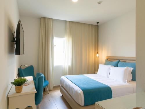 um quarto de hotel com uma cama e uma cadeira em Santa Cruz Boutique Hotel em Mindelo