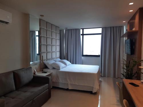 サルバドールにあるOITO ZERO UM - Flat Sol Victoria Marinaのベッドとソファ付きのホテルルーム