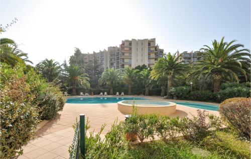 a swimming pool with palm trees and a large building at Nice Apartment In Mandelieu-La-Napoule in Mandelieu-la-Napoule
