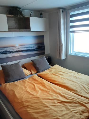 a bed with two pillows on it in a bedroom at Chalet Zeewind in Oostkapelle