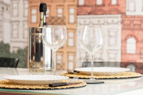 a table with two glasses and plates and a bottle of wine at Assago amazing flat in Assago