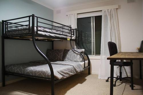 een slaapkamer met een stapelbed, een bureau en een bureau bij Gum Lodge, Gateway to the Murray in Loxton