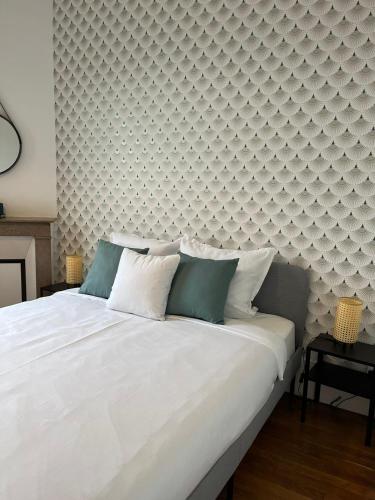 - une chambre avec un grand lit blanc et un mur dans l'établissement VILLEMOMBLE 2 centre ville, à Villemomble