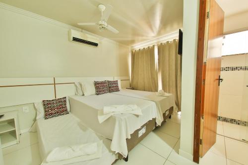 a white bedroom with a bed and a window at Apartamento Mont Sião II in Porto Seguro