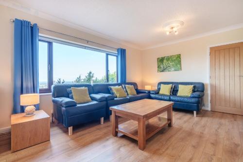 a living room with a blue couch and a table at Offa's Lodge Family home quiet area with sea views in Prestatyn