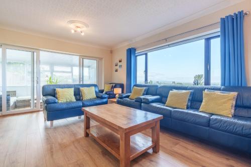 a living room with blue couches and a table at Offa's Lodge Family home quiet area with sea views in Prestatyn