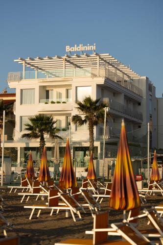 a group of chairs with umbrellas in front of a building at Baldinini Hotel in Rimini