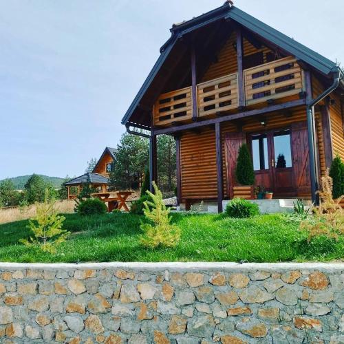 a log cabin with a stone wall in front of it at Vila Vodice Zlatibor in Vodice