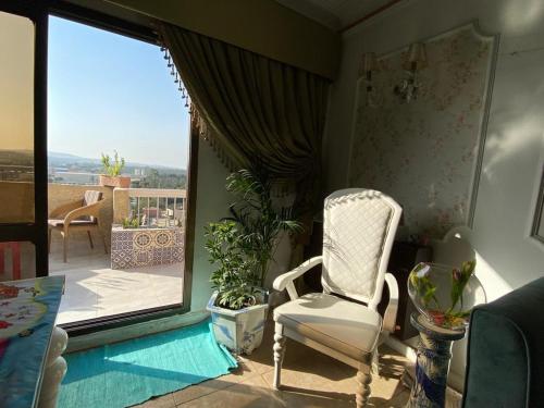 Una silla blanca en una habitación con balcón en GEM & Pyramids Entire Apartment, en El Cairo