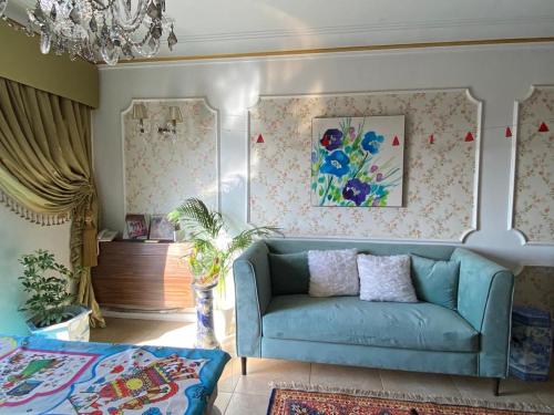 sala de estar con sofá azul y lámpara de araña en GEM & Pyramids Entire Apartment, en El Cairo