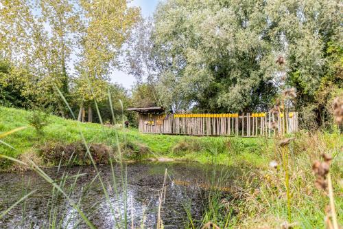 a wooden hut on a hill next to a river at Casa Marit in Westouter