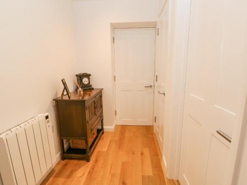 a hallway with a clock on a dresser and a door at James' Place in Falmouth