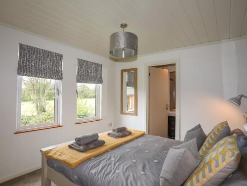 a bedroom with a bed and two windows at 32 Sanctuary Lodge in Pwllheli
