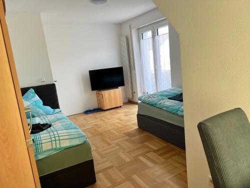Habitación pequeña con 2 camas y TV. en Guesthouse David, en Augsburg