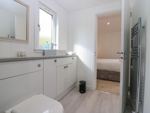 Baño blanco con lavabo y espejo en Lodge 16 - The Ericht Family, en Perth