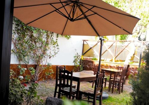 a table and chairs under an umbrella in a garden at La casa de theo in Arequipa