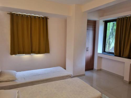 a bedroom with two beds and a window at Cinnamon House in Pune