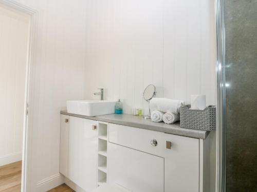 a white bathroom with a sink and towels on a counter at Lodge 18 - Ruthven Hideaway in Perth