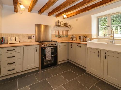 a kitchen with white cabinets and a sink and an oven at 1 White House Cottages in Ross on Wye
