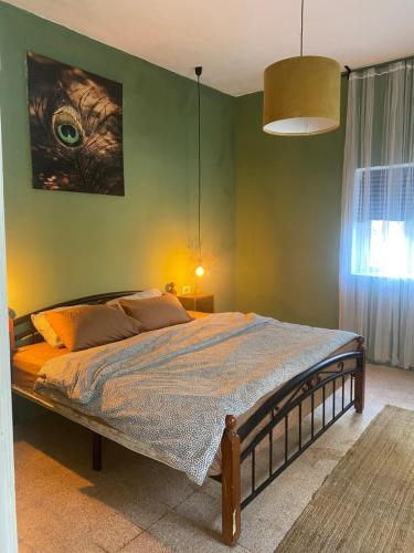 a bed in a bedroom with a green wall at Cozy apartment near Paris square in Amman