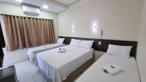 a hotel room with two beds and a window at Pousada Barbosa in Aparecida