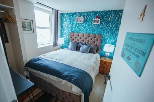 a bedroom with a bed with blue walls and a window at KENDAL HOLIDAY FLATS in Kendal