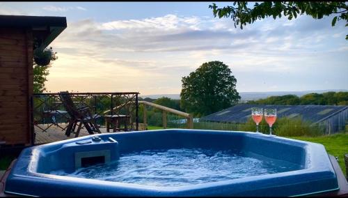 a blue hot tub with two glasses of wine at Cherry Tree Glamping Lodge in Wellington